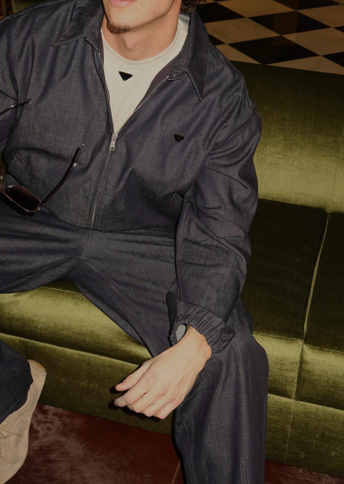 A high-altitude sourcing visual of the Prada SS26 Menswear denim ensemble. Captured during an in-boutique verification session to confirm the textile integrity and batch-specific detailing of the upcoming collection.